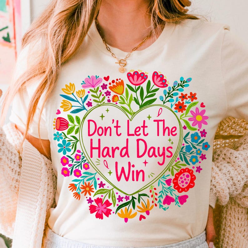 Close-up of 'Don't Let The Hard Days Win' PNG design featuring a preppy floral heart, positive affirmation text, and vibrant retro wildflowers, ideal for Mental Health Awareness Month crafts.
