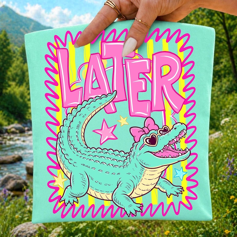 A vibrant Later Gator PNG digital design featuring a stylized teal alligator with heart-shaped sunglasses and a coquette bow, set against a bold pink and neon yellow striped background.