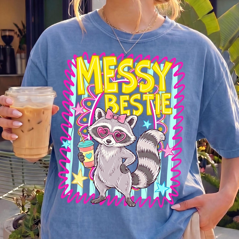 Close-up of the "Messy Bestie Raccoon" PNG design with heart glasses and iced coffee.