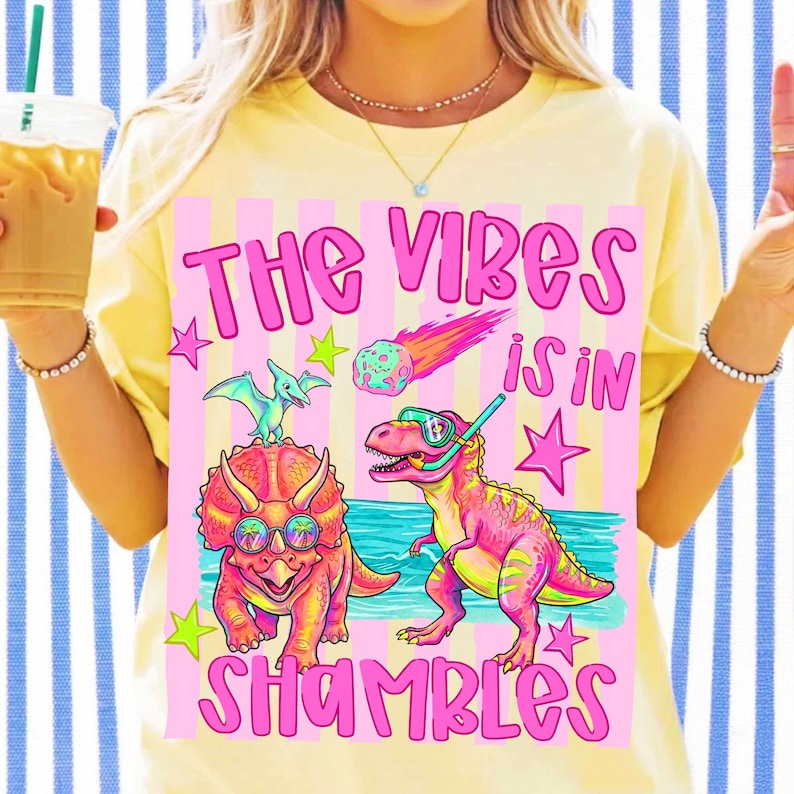 The Vibes Is In Shambles Dinosaur PNG design featuring a T-Rex and Triceratops on a retro neon beach.