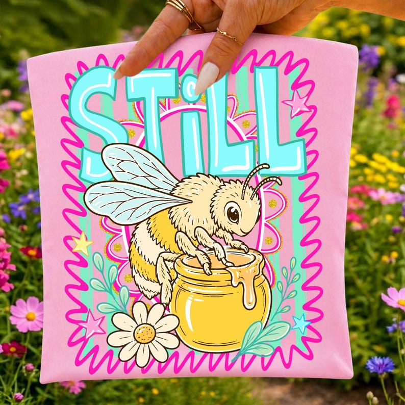 Bee Still Jesus PNG design on a white t-shirt, showcasing the retro striped bee and faith message.